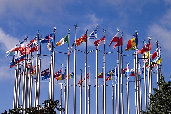 A circle of flagpoles flying European flags.